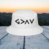 God is greater than embroidered bucket hat on a wooden table with a sunset background.