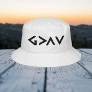 God is greater than embroidered bucket hat on a wooden table with a sunset background.