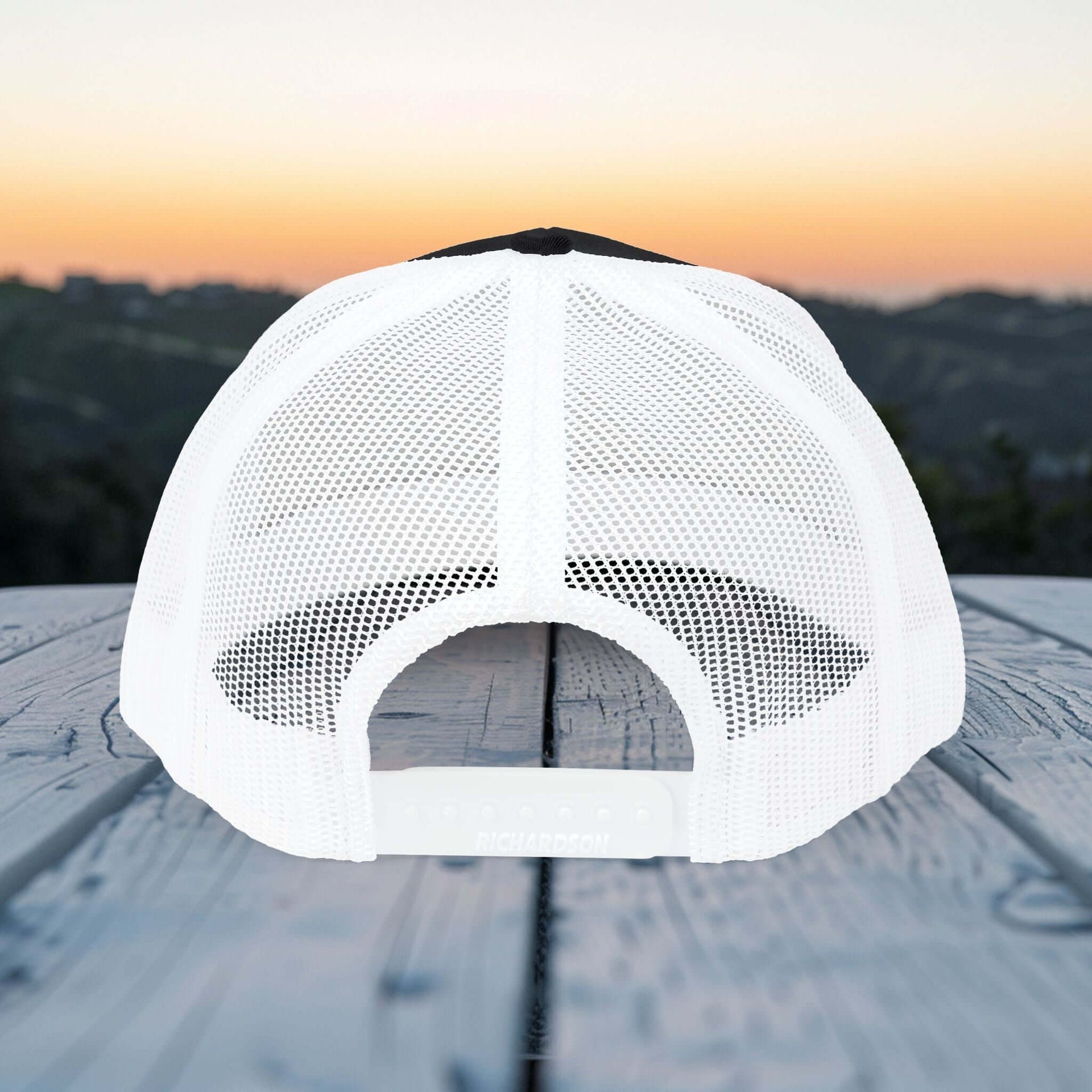Back view of Believe In Christ Snapback Hat showcasing breathable mesh design against sunset backdrop.