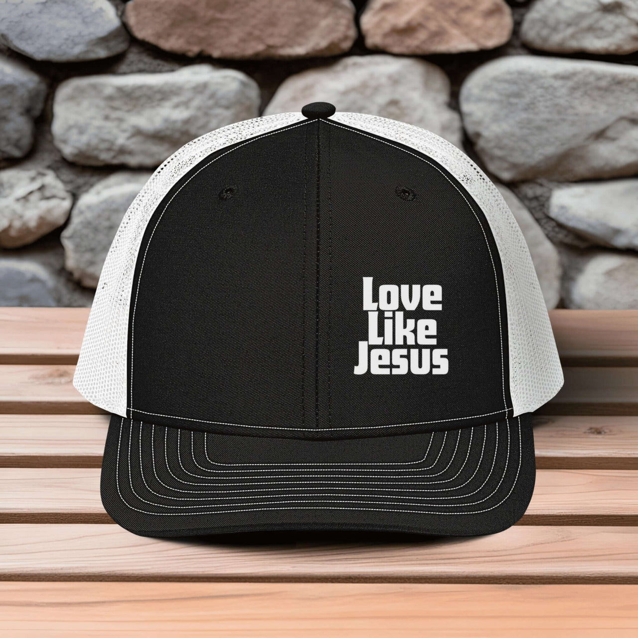 Love Like Jesus snapback hat featuring bold embroidery against a stone background.