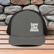 Love Like Jesus snapback hat featuring bold white embroidery on a gray trucker hat.