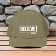 Believe In Christ Snapback Hat in olive green with embroidered design on wooden table