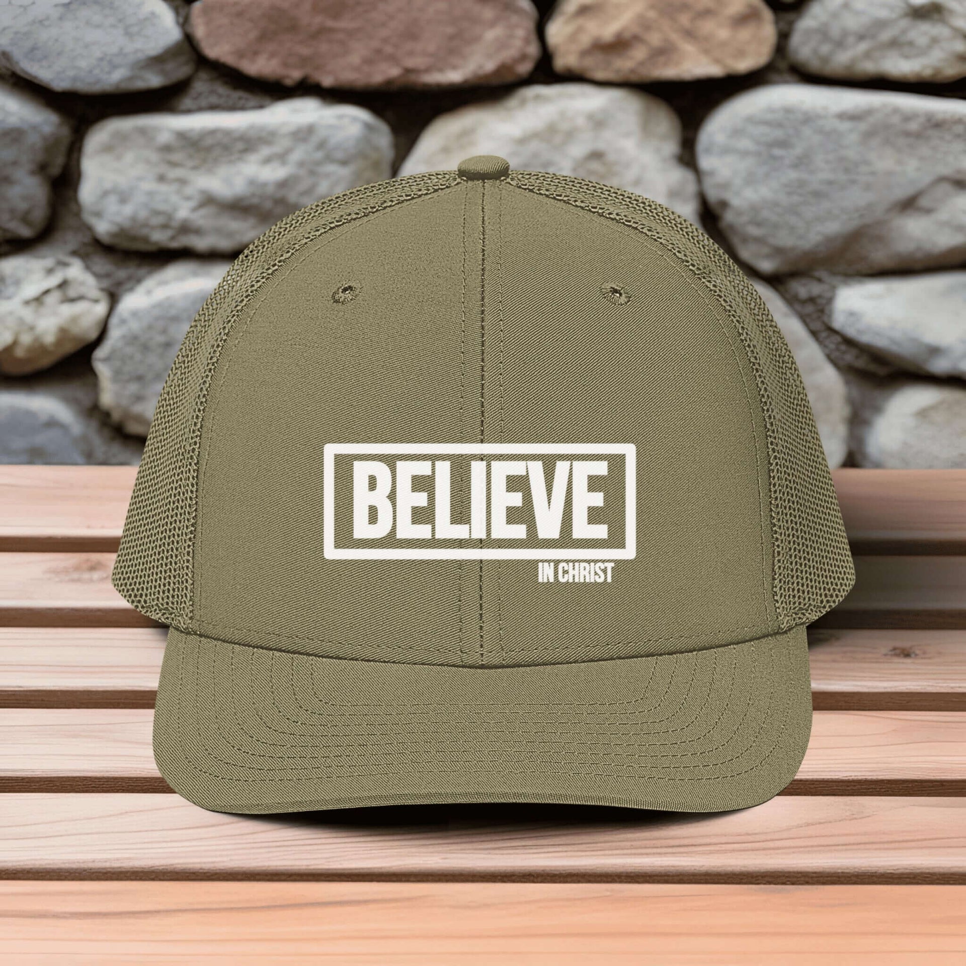 Believe In Christ Snapback Hat in olive green with embroidered design on wooden table