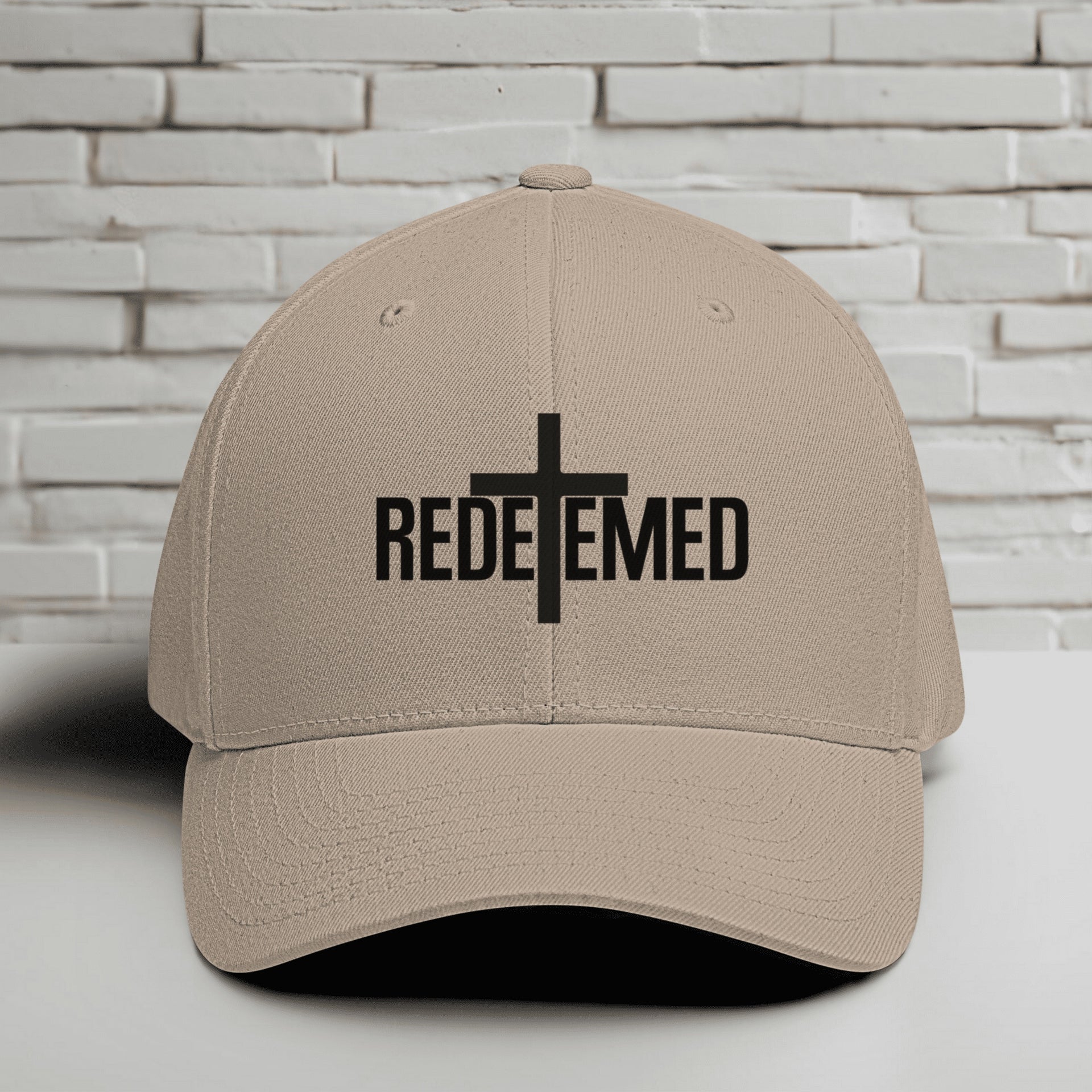 Redeemed Embroidered Flexfit Hat featuring the word Redeemed and a cross design on a khaki cap.
