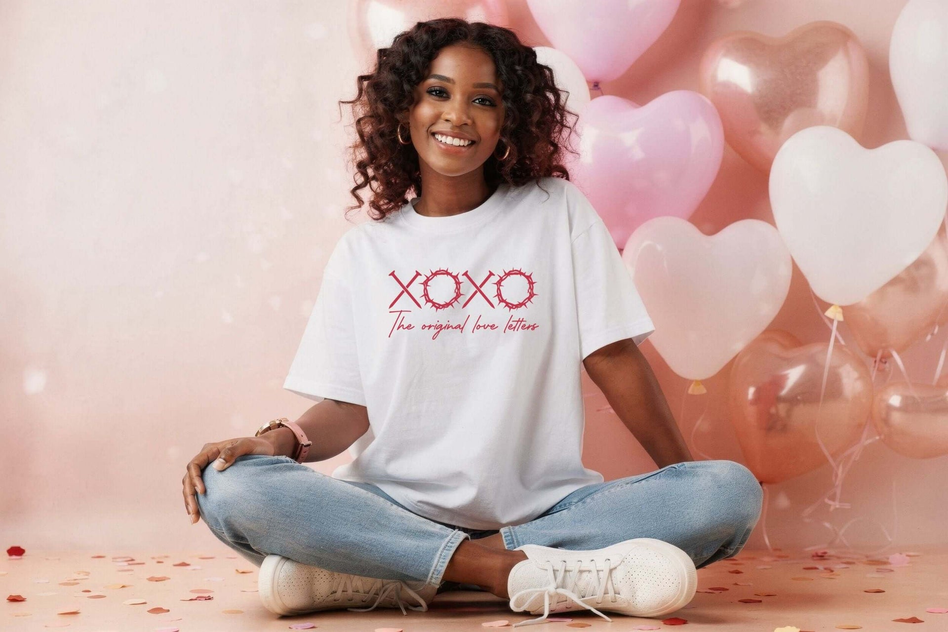 XOXO The Original Love Letters Tee Crown of Thorns Shirt worn by a smiling woman among heart-shaped balloons.