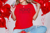 Woman holding a glass wearing XOXO The Original Love Letters Tee Crown of Thorns Shirt with red balloons.