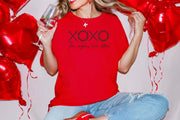 Woman holding a glass wearing XOXO The Original Love Letters Tee Crown of Thorns Shirt with red balloons.
