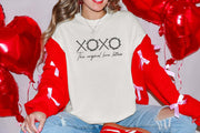 XOXO The Original Love Letters Tee Crown of Thorns Shirt worn with colorful red jacket surrounded by heart balloons.
