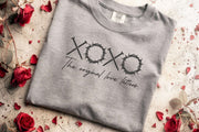 XOXO The Original Love Letters Tee Crown of Thorns Shirt displayed on a grey shirt surrounded by red rose petals.