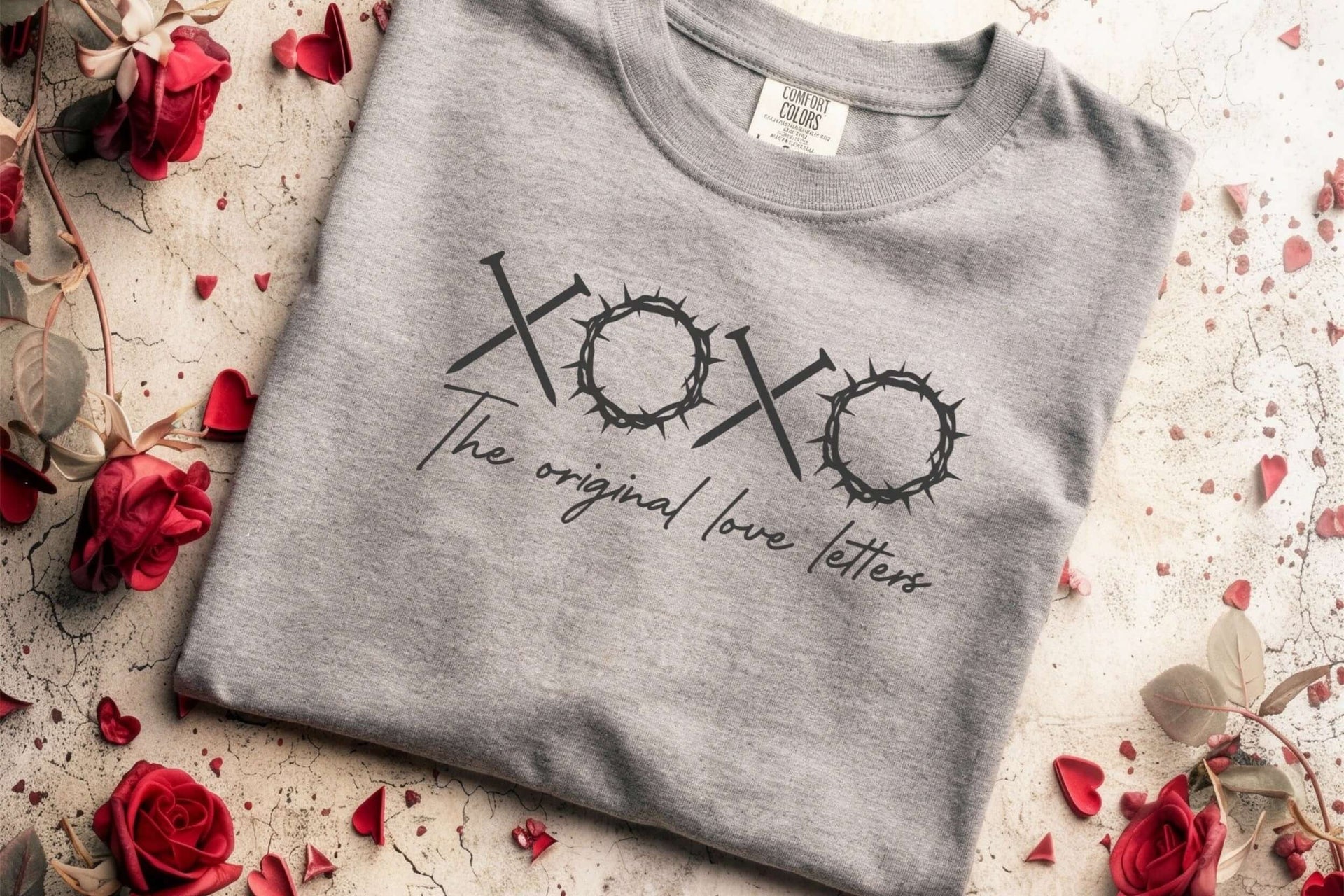 XOXO The Original Love Letters Tee Crown of Thorns Shirt displayed on a grey shirt surrounded by red rose petals.