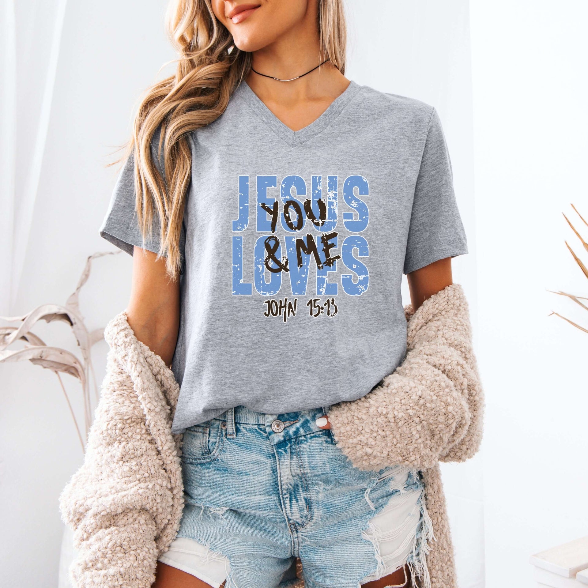 Model wearing a Jesus Loves You & Me T-shirt featuring John 15:13, in a casual setting with a cozy cardigan.