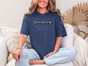 Jesus Loves Me Unisex T-shirt model wearing navy graphic tee in a cozy living room setting.