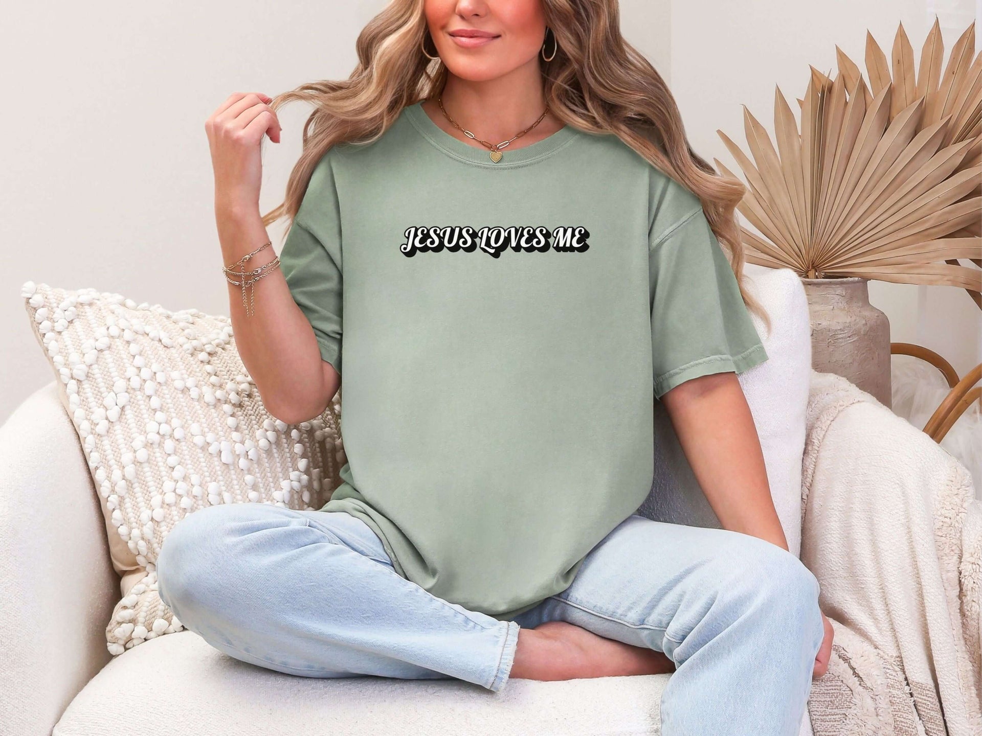 Jesus Loves Me Unisex T-shirt styled in a comfortable, relaxed fit worn by a woman sitting casually at home.