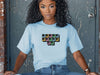 Jesus Loves Me Unisex T-Shirt featuring keyboard keys graphic on a woman sitting casually.
