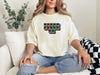 Jesus Loves Me Unisex T-Shirt displayed on a model sitting on a couch, featuring a keyboard keys graphic.