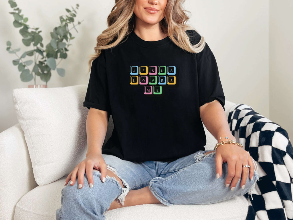 Jesus Loves Me Unisex T-Shirt featuring keyboard keys graphic on a model sitting on a sofa.