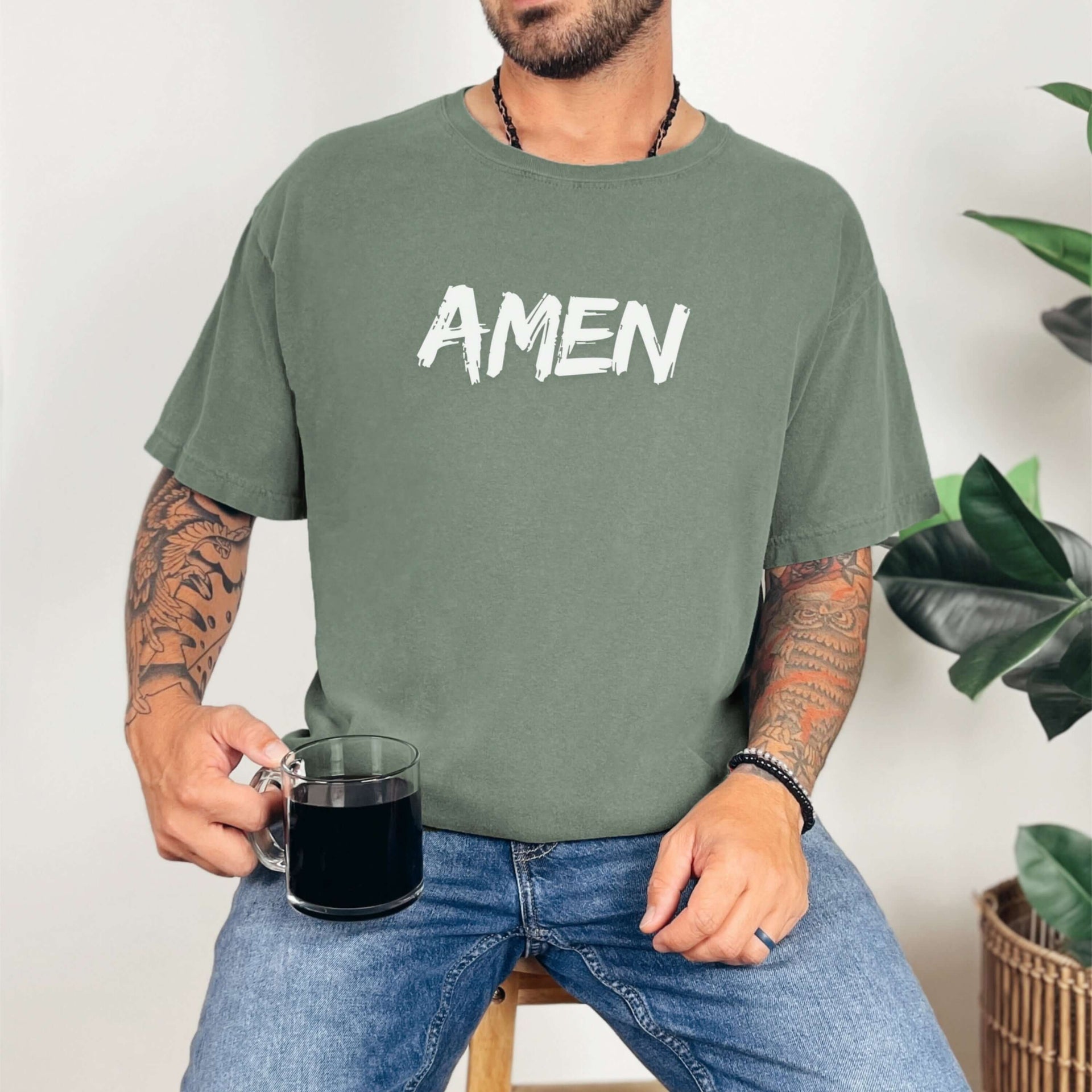Amen Brush Stroke Text T-Shirt worn by man holding coffee, featuring bold 'AMEN' text in a minimalist design.