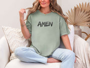 Amen Brush Stroke Unisex T-shirt worn by a woman, showcasing a bold "AMEN" print on a bay tee.