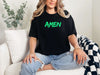 Amen Brush Stroke Unisex T-shirt worn by a woman, featuring bold 'AMEN' in green on a black tee.