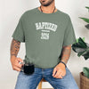 Person wearing a Baptized 2026 T-Shirt in moss while holding a cup of coffee.