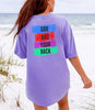 God Has Your Back T-Shirt displayed on a model by the beach with a vibrant color block design.