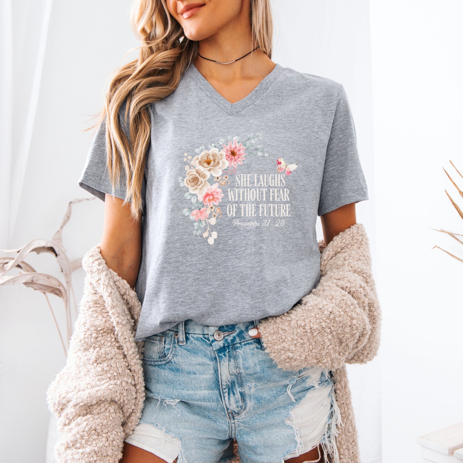 She Laughs Without Fear Of The Future V Neck Tee with floral design, worn casually by a woman in a cozy setting.