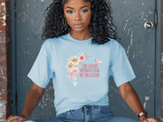 She Laughs Without Fear Of The Future Floral T Shirt in light blue with floral design worn by a woman.
