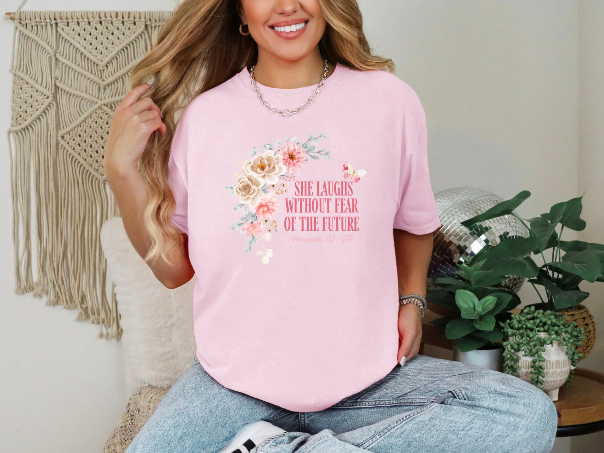 A woman wearing a pink She Laughs Without Fear Of The Future Floral T Shirt with a floral design, smiling confidently.