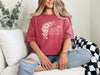 She Laughs Without Fear Of The Future Floral T Shirt worn by a woman with a floral design, sitting casually on a couch.