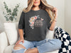 She Laughs Without Fear Of The Future Floral T Shirt worn by a woman sitting on a couch with floral design and Proverbs 31:25.