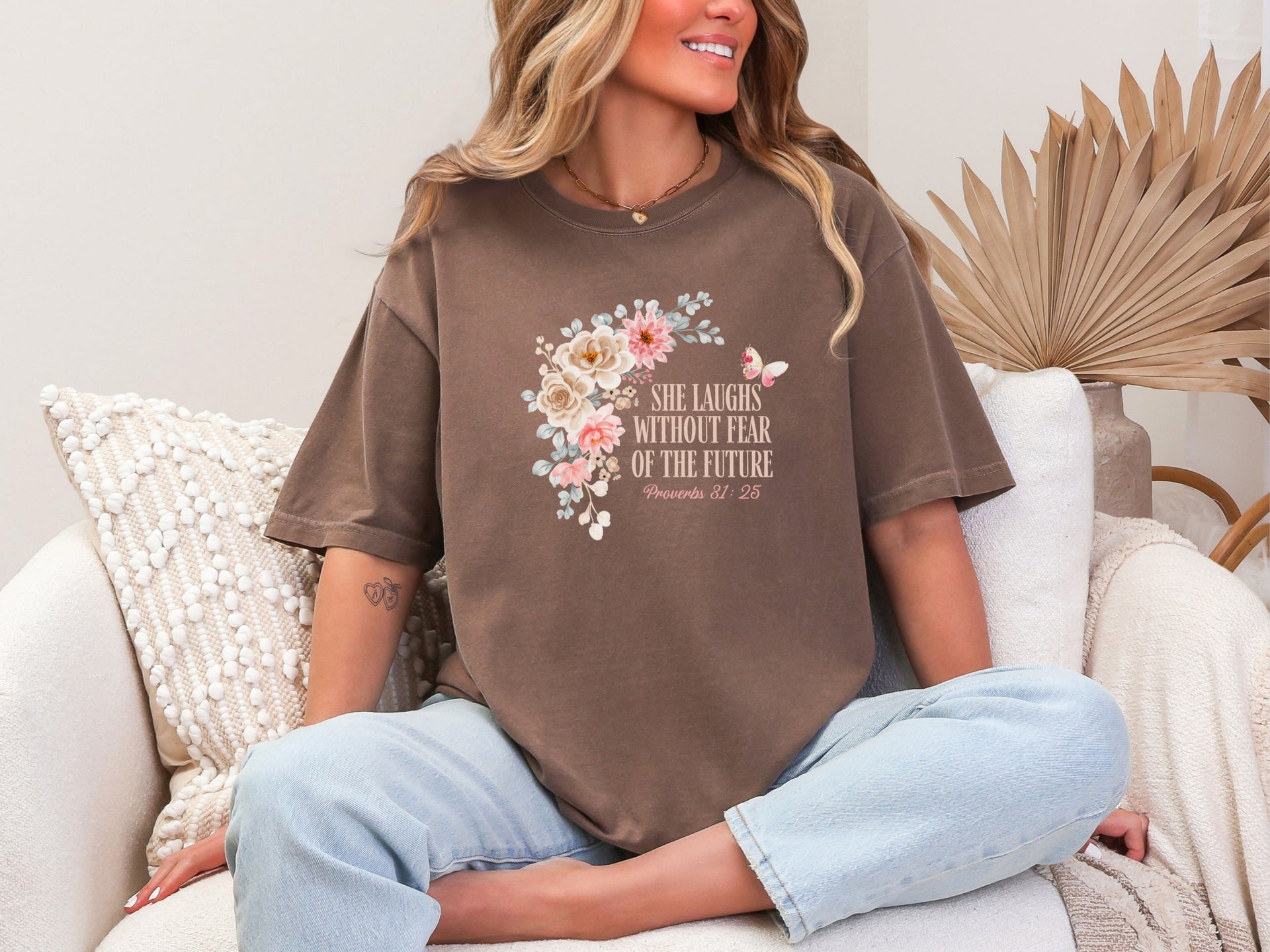 Woman wearing She Laughs Without Fear Of The Future Floral T Shirt with floral design and a cozy background.