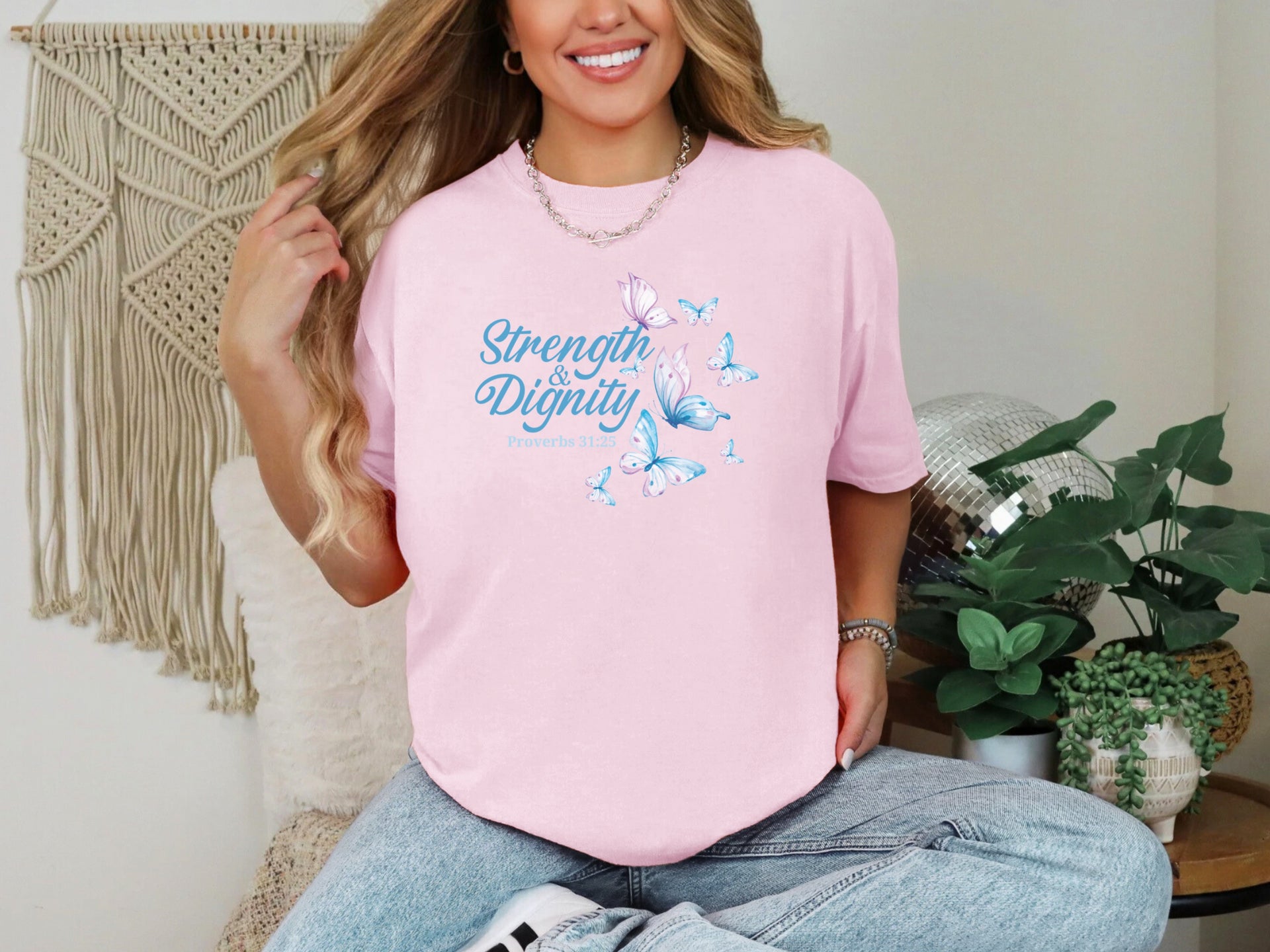 Strength And Dignity Proverbs 31 25 Butterfly T Shirt worn by a smiling woman, featuring a butterfly graphic in a soft pink color.