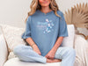 Strength And Dignity Proverbs 31 25 Butterfly T Shirt displayed by a woman sitting on a couch.