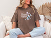 Strength And Dignity Proverbs 31 25 Butterfly T Shirt worn by a smiling woman sitting on a couch with butterflies design.
