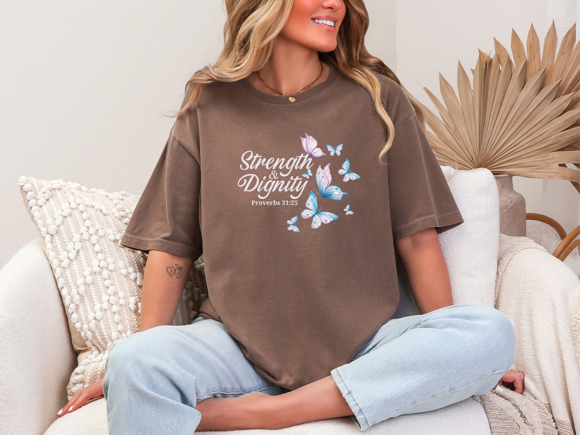 Strength And Dignity Proverbs 31 25 Butterfly T Shirt worn by a smiling woman sitting on a couch with butterflies design.
