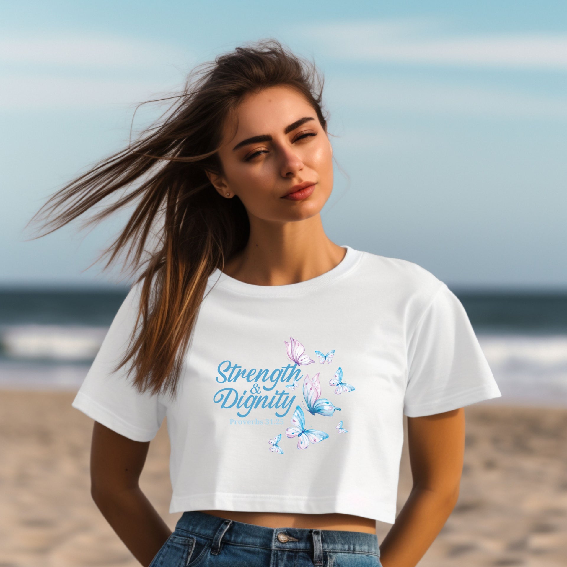 Strength And Dignity Proverbs 31 25 Butterfly Crop Tee worn by a woman on the beach with butterfly graphic.