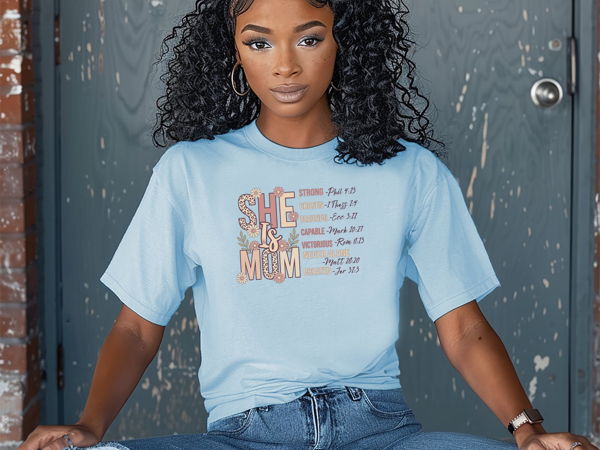 She Is Mom Floral Typography T Shirt displayed by a model, featuring soft floral design and comfortable unisex fit.