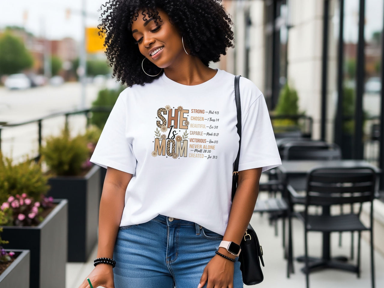 She Is Mom Floral Typography T Shirt worn by a smiling woman in casual setting with floral design.