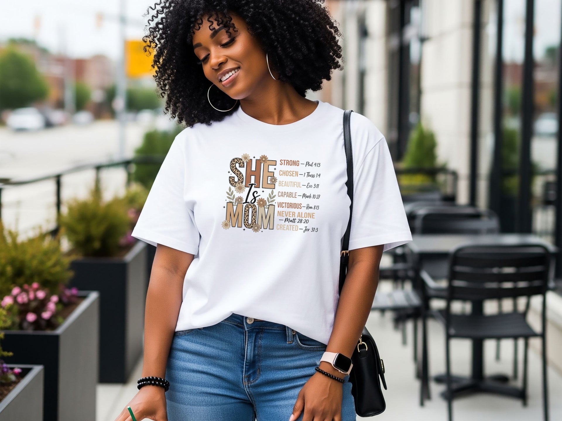 She Is Mom Floral Typography T Shirt worn by a smiling woman in casual setting with floral design.