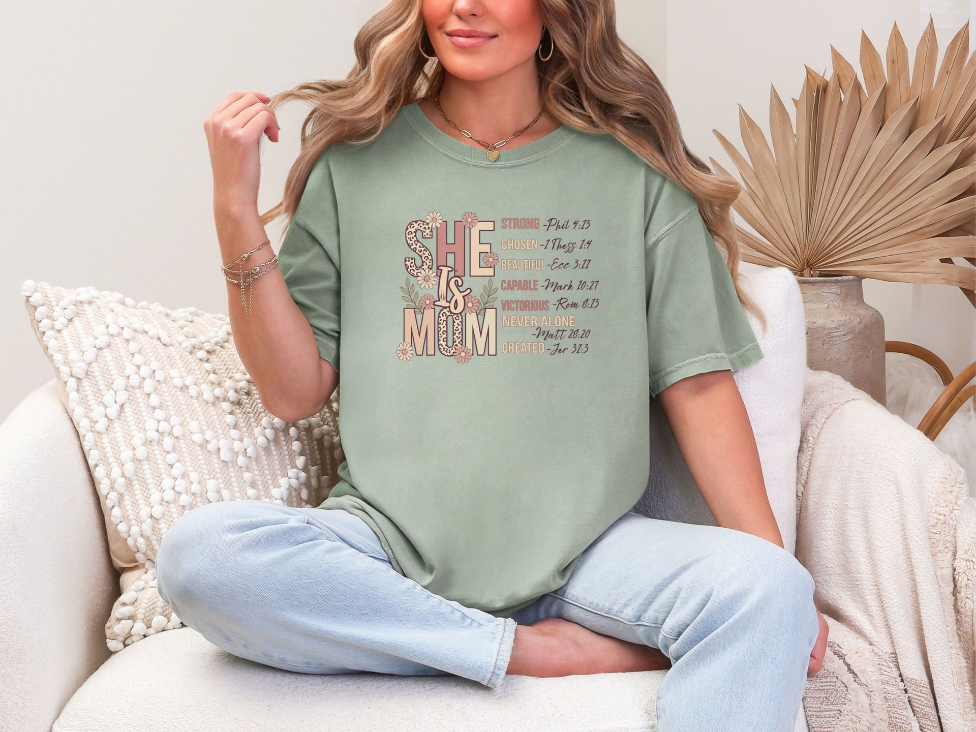 She Is Mom Floral Typography T Shirt modeled by a woman in a cozy setting, showcasing its unique design and comfortable fit.