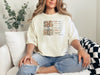 She Is Mom Floral Typography T Shirt worn by a woman, featuring a design that celebrates motherhood with floral typography.