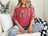 She Is Mom Floral Typography T Shirt worn by a woman in a cozy setting, showcasing the unique floral design.