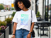 SHE IS vertical affirmation mom T-Shirt worn by a smiling woman outdoors, showcasing uplifting typography design.