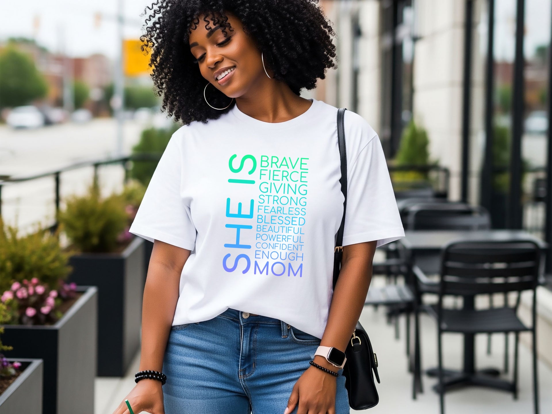 SHE IS vertical affirmation mom T-Shirt worn by a smiling woman outdoors, showcasing uplifting typography design.