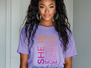 SHE IS vertical affirmation mom T-Shirt featuring uplifting typography in vibrant colors on a model.