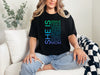 A woman wearing a SHE IS vertical affirmation mom T-Shirt with positive affirmations, showcasing strength in motherhood.