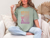 Woman wearing SHE IS vertical affirmation mom T-Shirt with uplifting words celebrating motherhood.