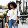 Woman wearing a Trust God With Tomorrow T-Shirt, enjoying a drink while walking in a city setting.