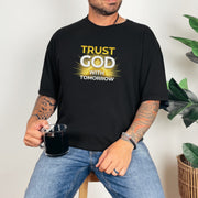 Person wearing a black shirt with the text 'Trust God With Tomorrow' while holding a mug.