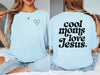 Model wearing a Cool Moms Love Jesus T Shirt featuring heart design and trendy font on the back.
